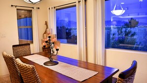 A dining area with a wooden table, woven chairs, a candle centerpiece, and large windows with curtains. -  SW STYLE/BREATHTAKING VIEWS & 8 Min. to OLD TWN~WOW REVIEWS/Long Term SPECIALS  (Albuquerque)