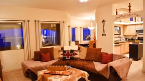 A living room with a sofa, ottoman, and a dining area with a table and chairs. -  SW STYLE/BREATHTAKING VIEWS & 8 Min. to OLD TWN~WOW REVIEWS/Long Term SPECIALS  (Albuquerque)