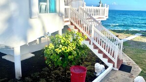 Un edificio blanco con una escalera que lleva a un balcón con vistas al océano.