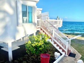 A white building with a staircase leading to a balcony overlooking the ocean. -  Oceanfront 2 Bedroom Villa in Guana Bay Sint Maarten; Ocnfrt Deck (Guana Bay)