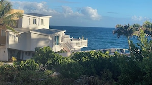 Un edificio frente al mar con un balcón y rodeado de vegetación.