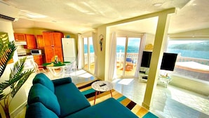 Una sala de estar con sofá, televisión y vista al mar.