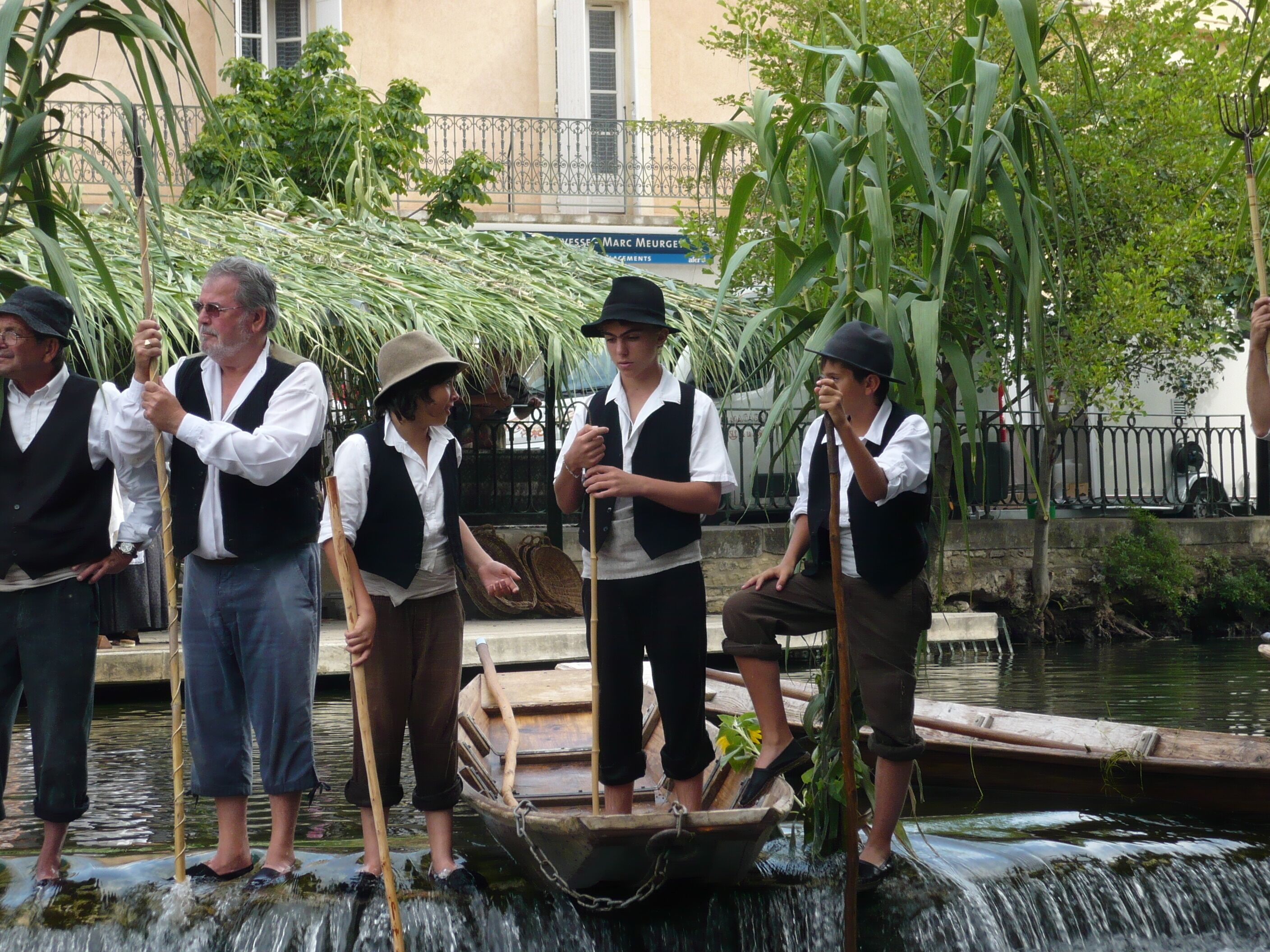 Un grup de persones amb vestimentes tradicionals al costat d'una font amb un vaixell.