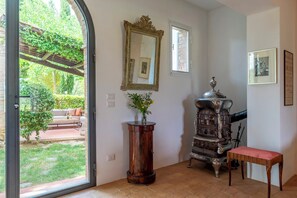 A room with a large window, a wooden table, a mirror, and a vintage stove.