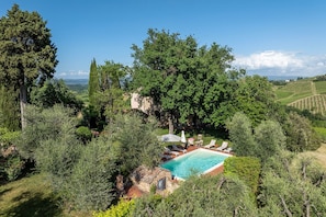 A pool surrounded by lush greenery and a stone building.