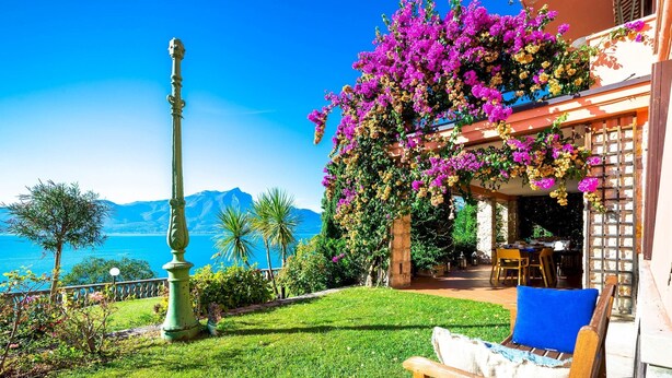A terrace with a view of the sea, a pergola with flowers, and a dining area. - Corazza 6+1, Emma Villas (Torri del Benaco)