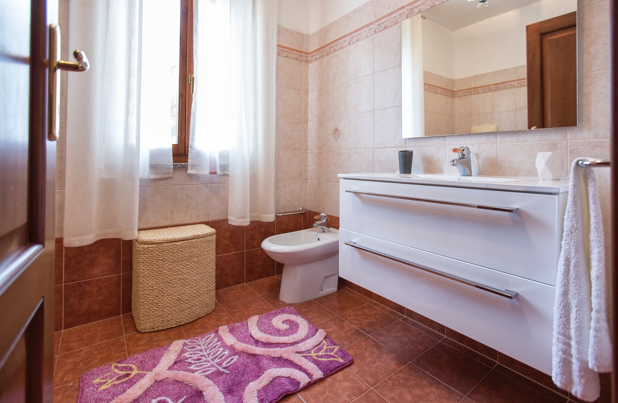 A bathroom with a bidet, a white sink, a mirror, and a towel rack.