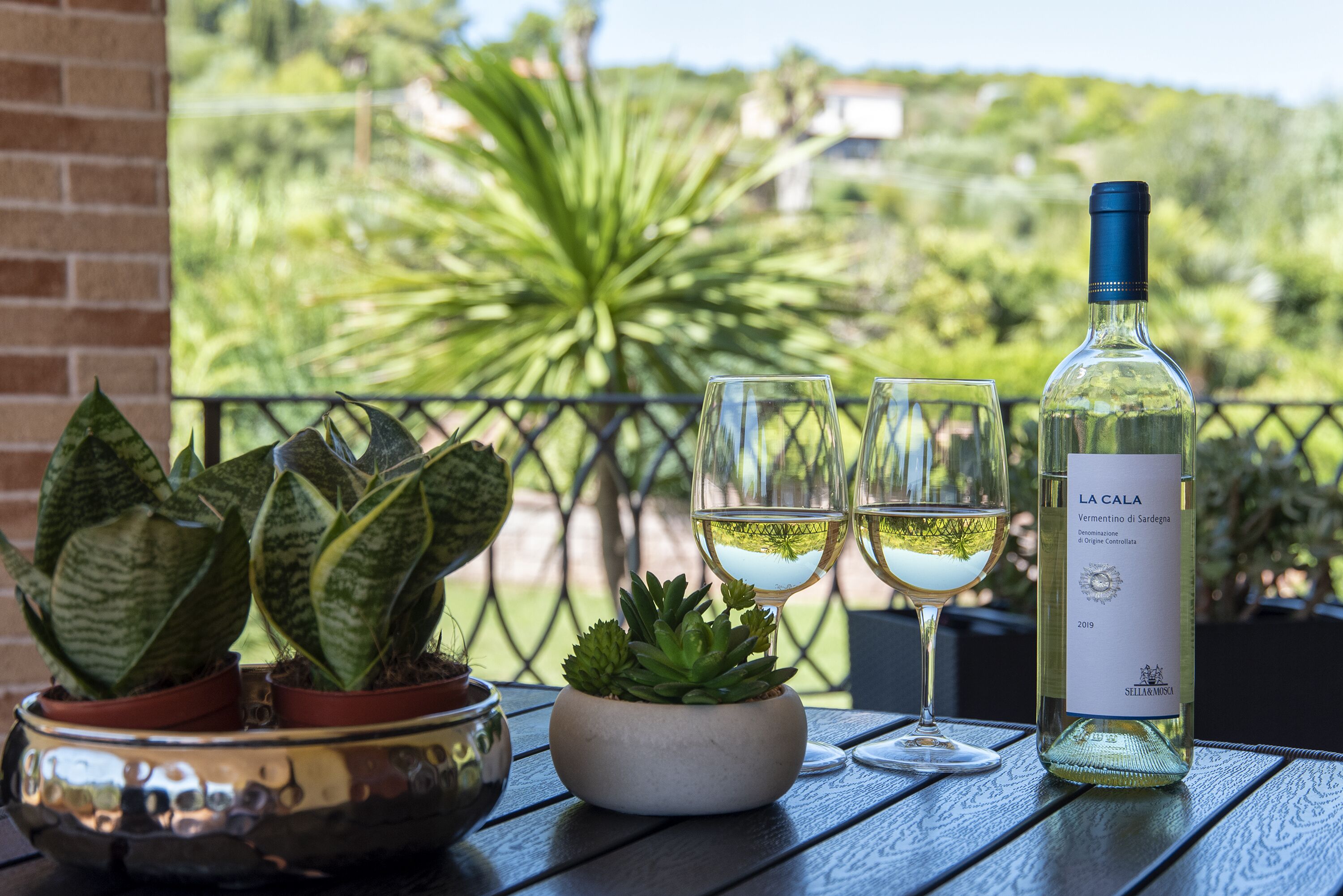 A table with a bottle of wine, two glasses, and a potted plant.