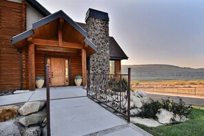A log cabin with a stone chimney, wooden door, and a metal fence. - BEAUTIFUL LOG HOME - CLOSE TO PARK CITY  (Coalville)