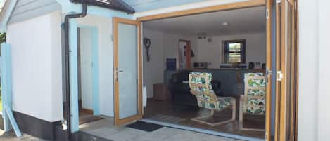 A house with a patio area, a dining table, and a kitchen visible through an open door.