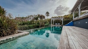 A clear blue pool with a wooden deck and lounge chairs. - Zen Villa in residential area (Saint francois)