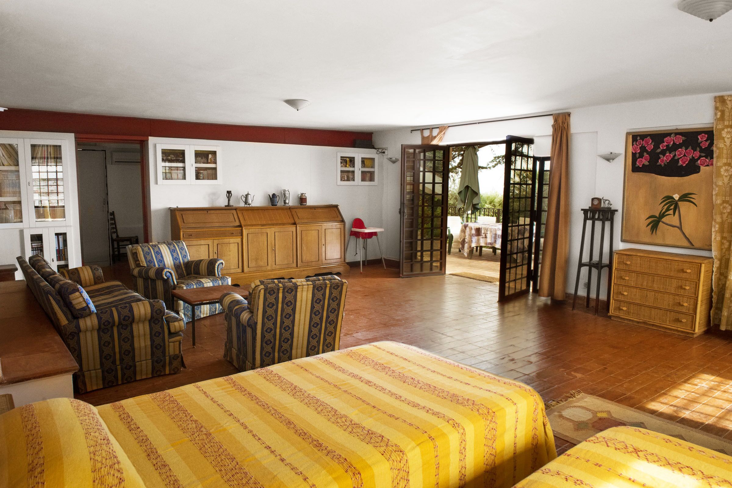 Una habitación amplia con una cama grande, un aparador de madera y un comedor con mesa y sillas.
