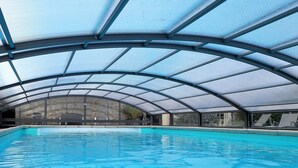 An indoor swimming pool with a glass ceiling and clear windows. - Beautiful stone house "country chic", private heated pool, play area (Membrey)