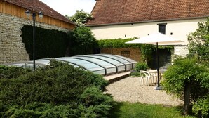 A courtyard with a greenhouse, stone wall, and a white umbrella. - Beautiful stone house "country chic", private heated pool, play area (Membrey)
