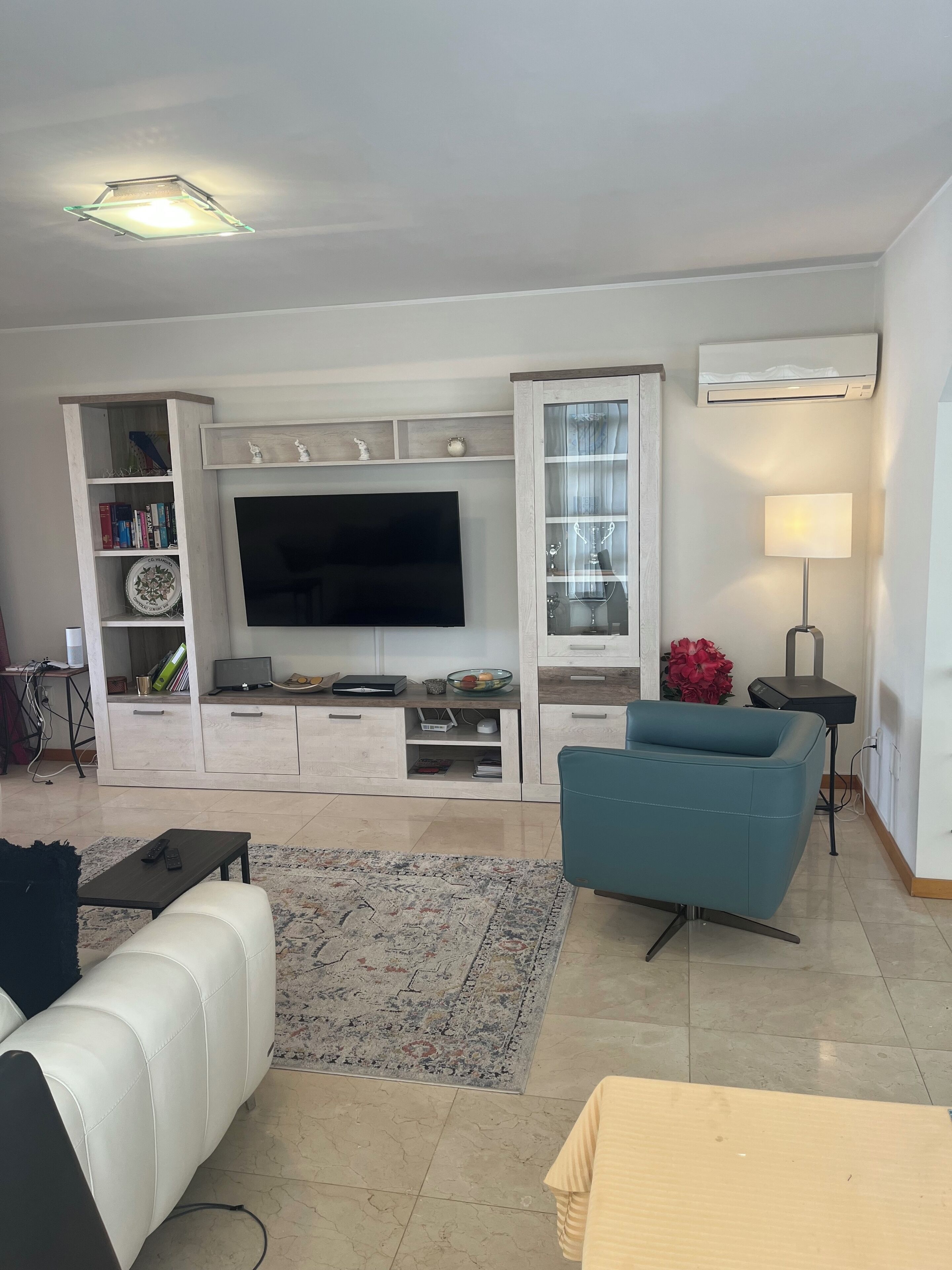 Een woonkamer met een flatscreen televisie, een bank, een salontafel en een lamp.
