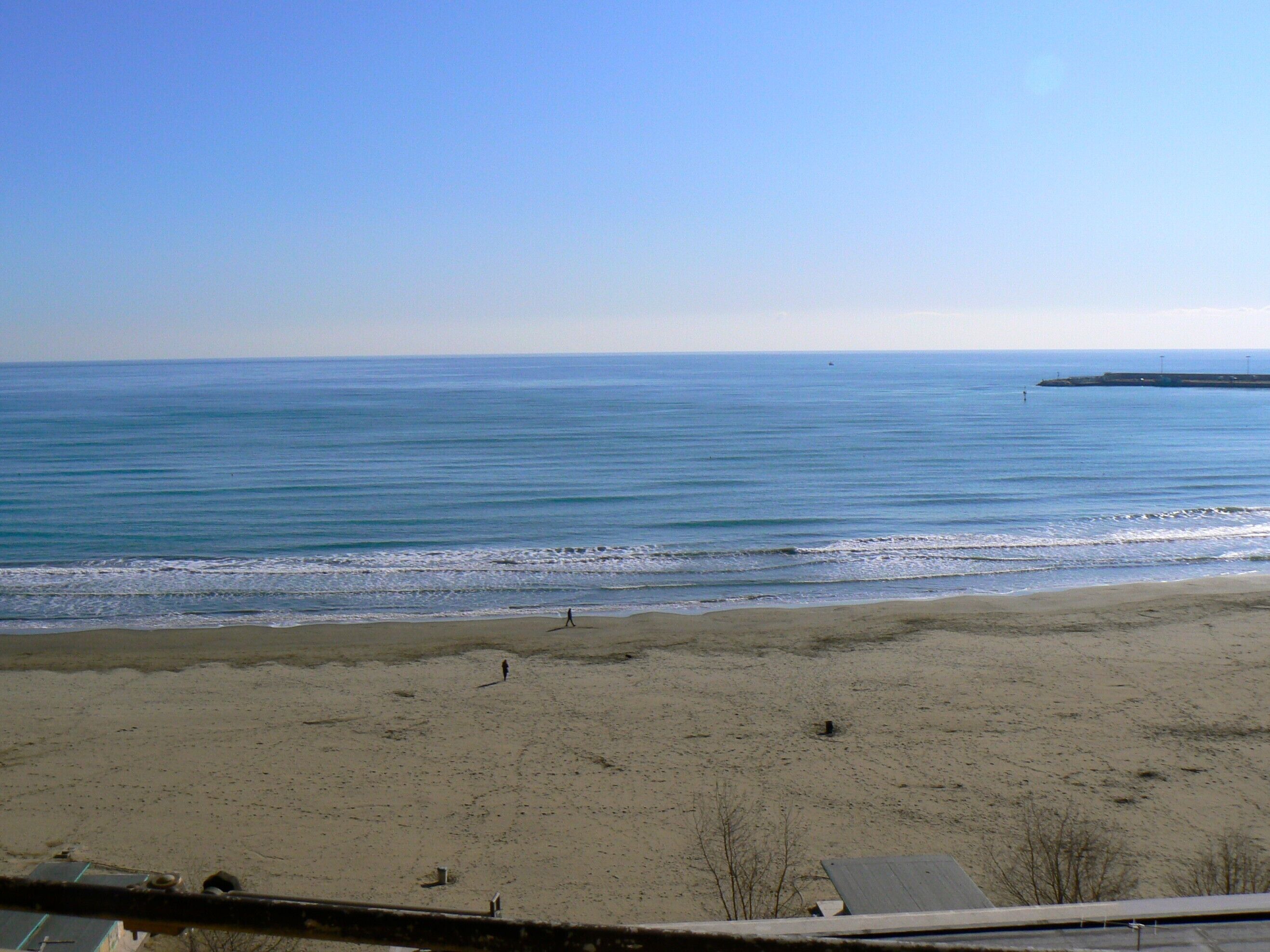 Une plage offrant une vue dégagée sur l’océan et sur une jetée située au loin.