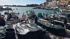 Un port avec des bateaux amarrés, un drapeau et des bâtiments en arrière-plan.