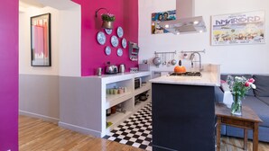 A modern kitchen with a black and white checkered floor, a pink accent wall, and various kitchen utensils and appliances. - Vittorio | Design and comfort in the center of Rome (Roma)