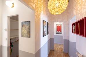 A hallway with artwork on the walls, a wooden floor, and a red bookshelf.