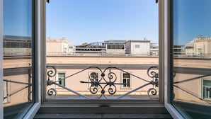 A view from a window with wrought iron balcony railings, overlooking a cityscape with buildings and a bridge. - Vittorio | Design and comfort in the center of Rome (Roma)
