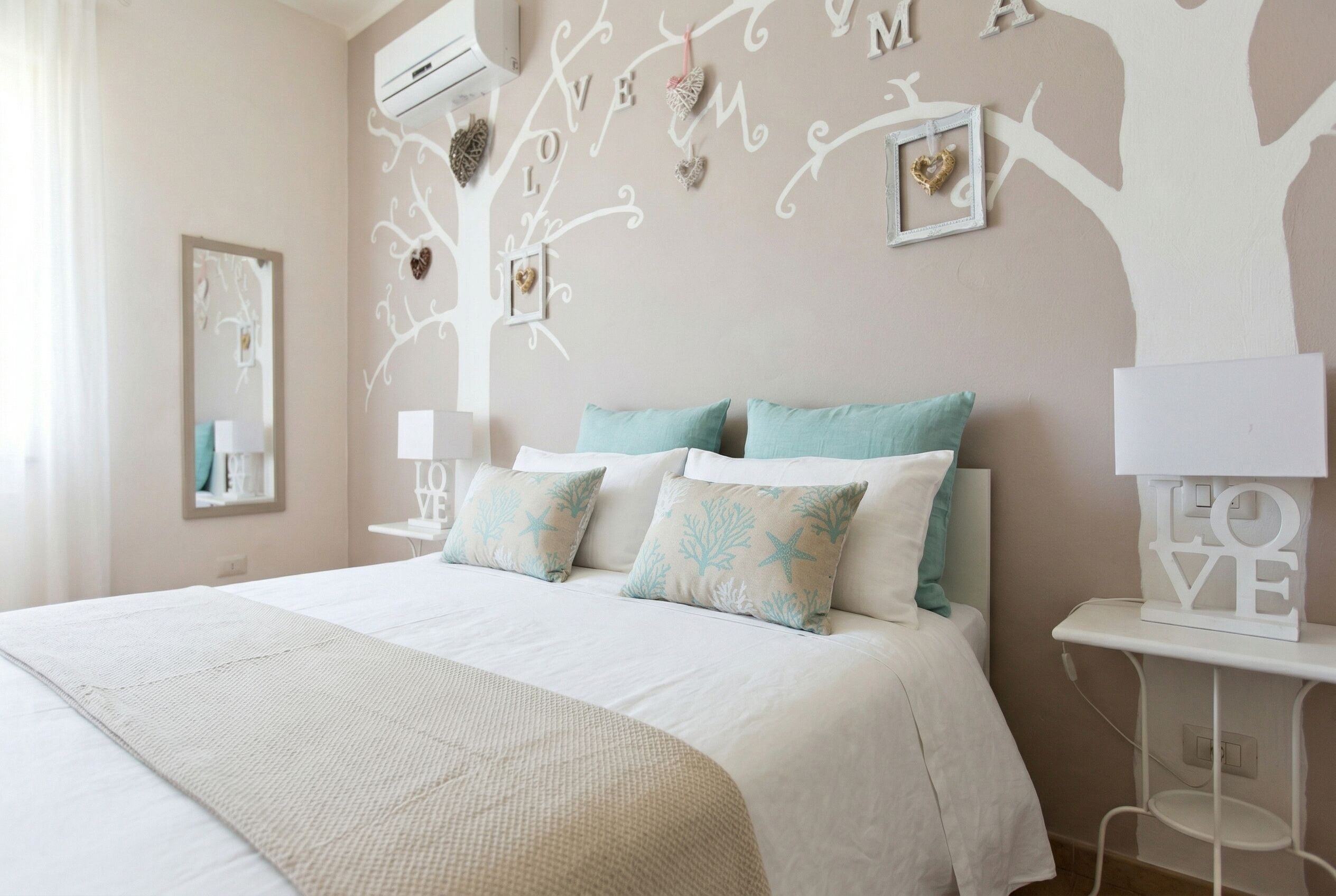 A bedroom with a bed, a nightstand, a wall-mounted air conditioner, and decorative wall art.