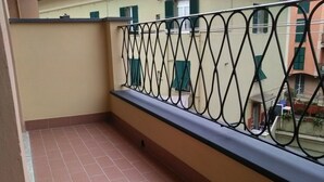 Un balcón con suelo de baldosas y barandilla metálica.