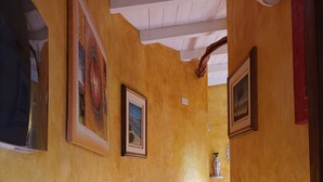 Ein Flur mit gelben Wänden, Fliesenboden und Decke mit weißen Holzbalken.