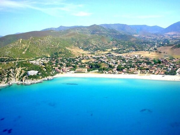 Eine Küstenstadt mit Strand, Gebäuden und Bergen im Hintergrund.