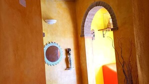 Eine Treppe führt zu einem hellen Raum mit einer gelben Wand, einem Spiegel und einer Vase.