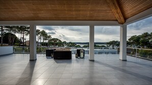 A spacious terrace with a view of a lake and trees, featuring a wooden ceiling and tiled flooring. - Luxury modern family villa with lagoon views, private heated pool, free wifi  (Foz do Arelho)