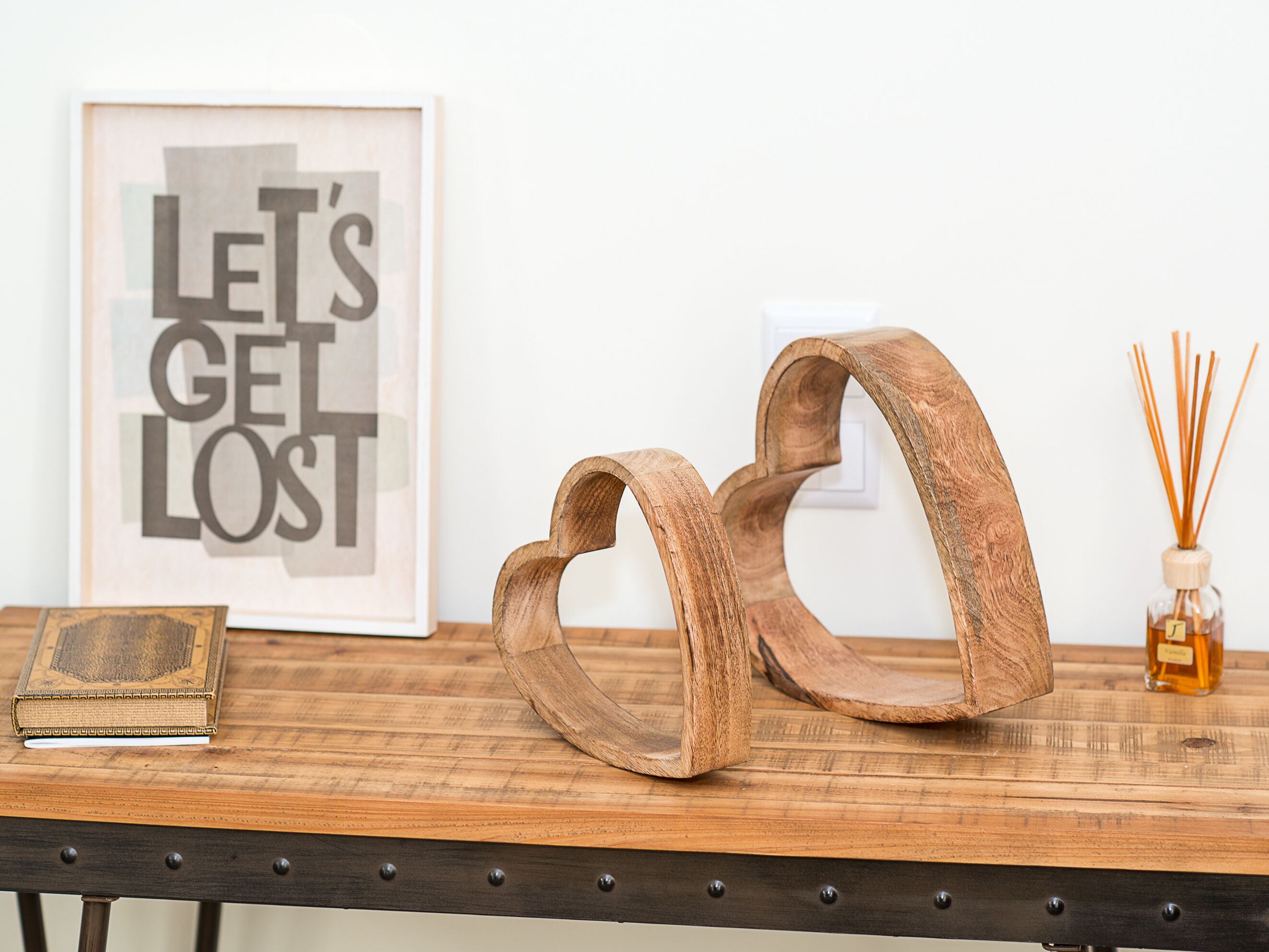 Une table en bois ornée de deux anneaux en bois, d’une citation encadrée, d’un livre et d’un diffuseur de parfum à bâtonnets.
