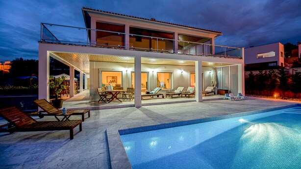 A modern two-story house with a swimming pool, outdoor seating, and a well-lit interior. - Luxury modern family villa with lagoon views, private heated pool, free wifi  (Foz do Arelho)