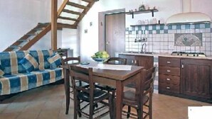 A cozy kitchen with wooden cabinets, a dining table, and a staircase leading to an upper level. - Mariuccia House Amalfi (Amalfi)