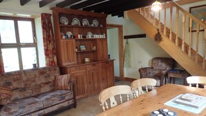 Una sala de estar acogedora con una mesa de comedor de madera, un sofá y una escalera.