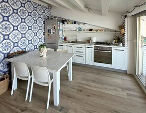 A modern kitchen with white cabinets, a dining table with chairs, and a patterned backsplash.