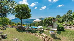 A pool area with lounge chairs, a wooden deck, and a view of mountains. - Borgo Paradiso 4+2, Emma Villas (Ciciano)