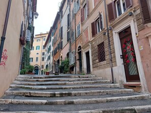 Eine schmale Gasse mit Steinstufen, die zu einem Gebäude mit einer verzierten Tür und einer Hausnummer führen.