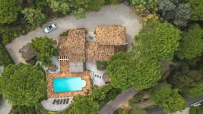 Vue aérienne d’une propriété dotée d’une piscine, d’une voiture garée dans l’allée et d’une terrasse en bois.