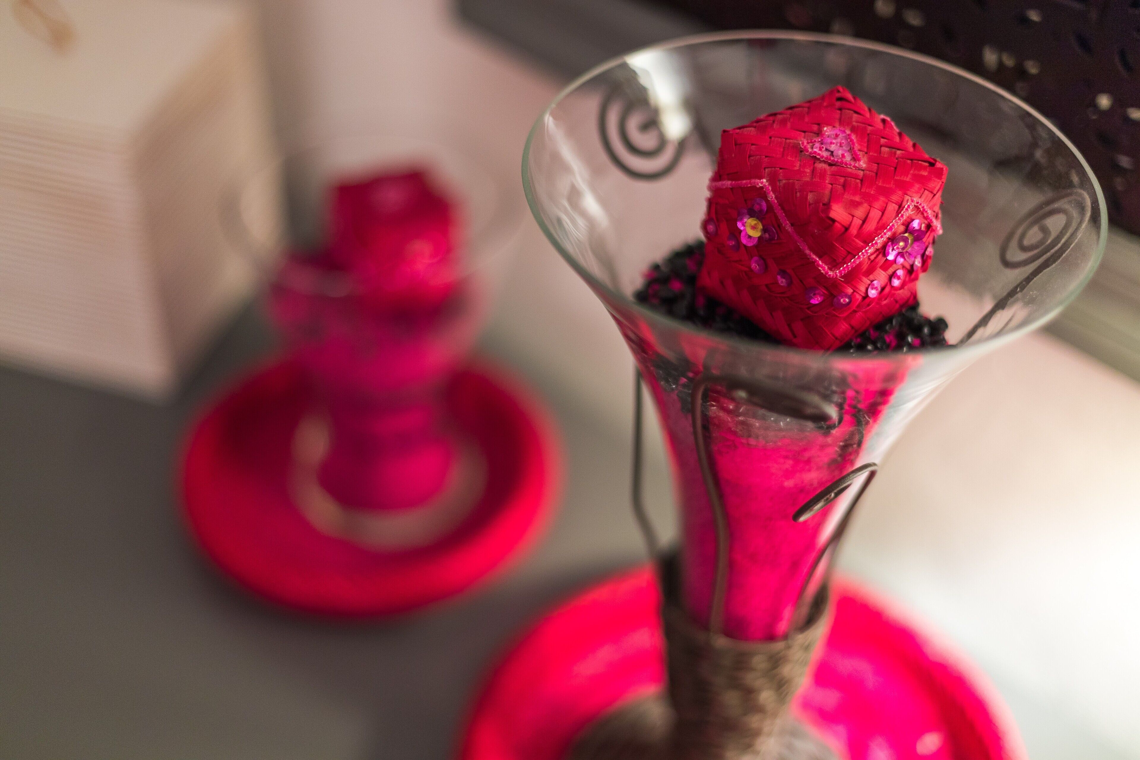 A glass dessert dish with a red, textured dessert and a decorative item in the background.