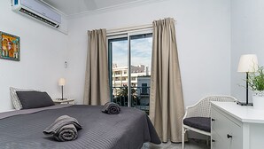 A hotel room with a large bed, a desk, a chair, and a view of buildings through the window. - GREAT HOUSE IN PARADOR AREA WITH POOL AND SEA VIEWS CLOSE TO BURRIANA AND CITY (Nerja)