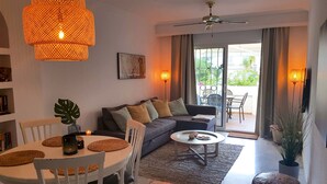 A modern living room with a sofa, dining table, and chairs. There is a ceiling fan, a large window with curtains, and a potted plant. - GREAT HOUSE IN PARADOR AREA WITH POOL AND SEA VIEWS CLOSE TO BURRIANA AND CITY (Nerja)