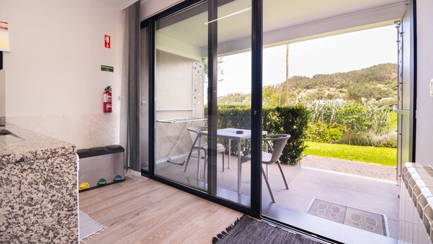 A modern room with a large sliding glass door leading to an outdoor patio area. - Studio north lower-level w/ kitchenett and patio (Santana)