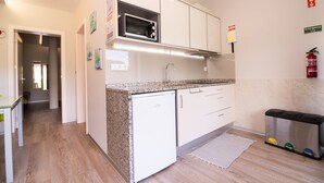 A compact kitchen with white cabinets, a microwave, a sink, and a trash bin. - Studio north lower-level w/ kitchenett and patio (Santana)