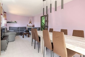A modern living room with a grey sofa, a dining table with six chairs, and a staircase leading to an upper floor. - House with pool, barbacue and garden, to 1500 meters from the fine sandy beach (Cubelles)