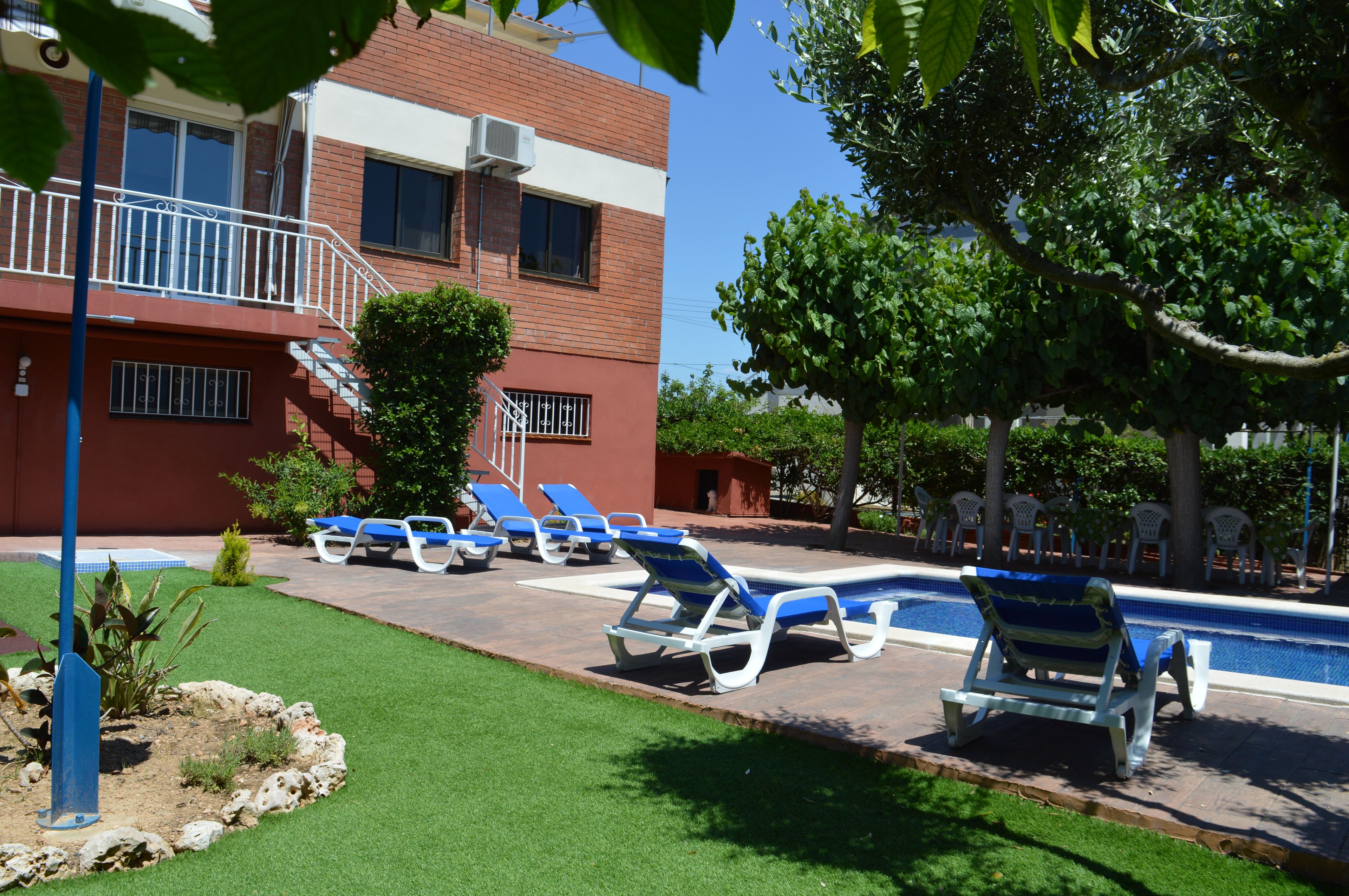 A pool area with lounge chairs and a building with a brick facade.