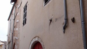 Eine schmale Gasse mit Gebäuden, die Rundbogenfenster und eine rote Tür zeigen.