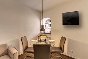 A modern dining area with a round glass table, two chairs, and a TV mounted on the wall. - Luxury suite Giulia, Stunningly refined apartment in the centre of Rome! (Roma)