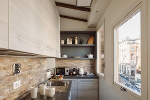 A modern kitchen with a stone backsplash, stainless steel appliances, and a view of the street through a large window. - Luxury suite Giulia, Stunningly refined apartment in the centre of Rome! (Roma)