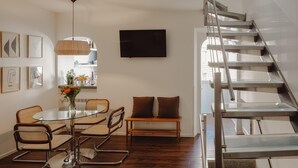 En modern inredning med ett matområde, en soffa, en trappa och en tv på väggen.
