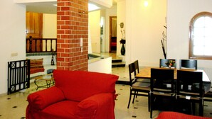 A living room with a red sofa, a dining table with chairs, and a brick fireplace.